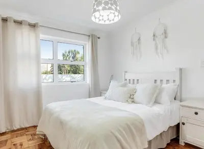 a white bedroom with a white bed and a window at Kiefern Haus Main House in Cape Town
