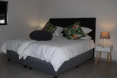 a bed with a black headboard and pillows on it at Villa Des Roses in Paarl