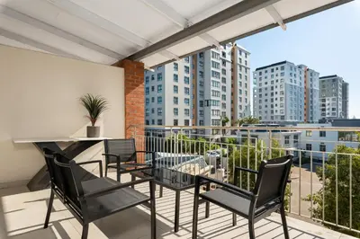 a balcony with chairs and a table and a view of buildings at Mayfair Apartments in Cape Town