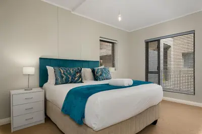 a bedroom with a large bed with a blue headboard at Mayfair Apartments in Cape Town