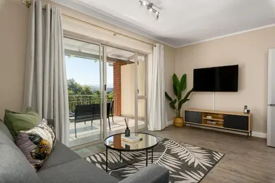 a living room with a couch and a tv at Mayfair Apartments in Cape Town