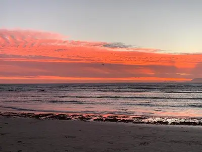 a sunset over the ocean with a sandy beach at Seaview on 2822 - Romantic Ocean Studio in Bettyʼs Bay