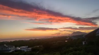a sunset over the ocean with houses and buildings at Seaview on 2822 - Romantic Ocean Studio in Bettyʼs Bay