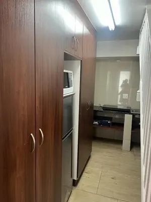 a kitchen with wooden cabinets and a microwave at Kiefern Haus Studio Apartment in Cape Town