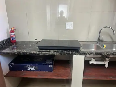 a kitchen counter with a sink and a laptop on it at Kiefern Haus Studio Apartment in Cape Town