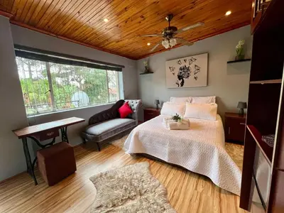 a bedroom with a bed and a couch and a window at SharronDeez in Cape Town