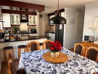 a kitchen with a table with a vase of flowers on it at Family Home in West Beach, Blouberg in Cape Town