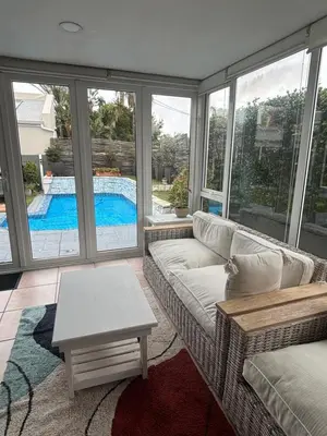 a living room with a couch and a table and a pool at Family Home in West Beach, Blouberg in Cape Town