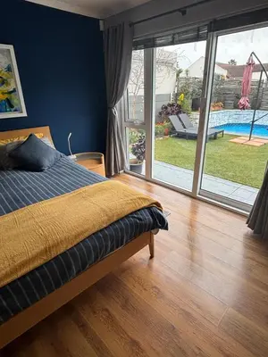 a bedroom with a bed and a view of a pool at Family Home in West Beach, Blouberg in Cape Town