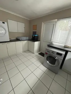a kitchen with a washing machine and a tiled floor at Family Home in West Beach, Blouberg in Cape Town