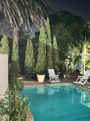 a swimming pool with two chairs and trees at Somerset West All Stay 3 in Somerset West