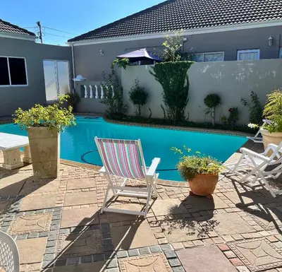 a patio with two chairs and a swimming pool at Somerset West All Stay 3 in Somerset West
