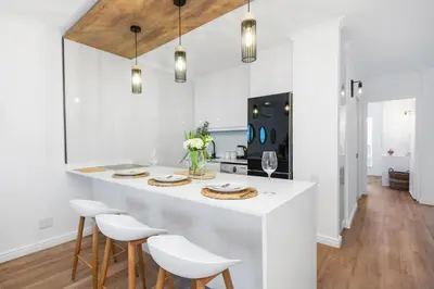 a kitchen with a white island with white stools at Leisure Bay 117 in Cape Town