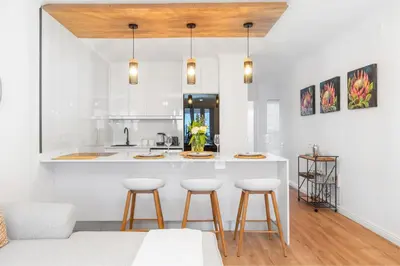 a kitchen with white walls and a counter with stools at Leisure Bay 117 in Cape Town