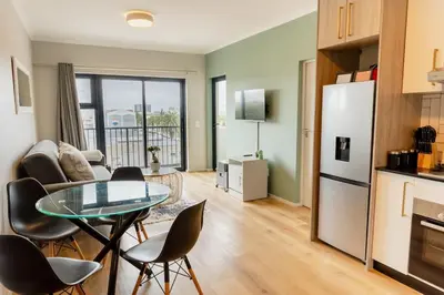 a kitchen and living room with a table and chairs at Sunny Beach Apartment with Sea & Mountain Views in Cape Town