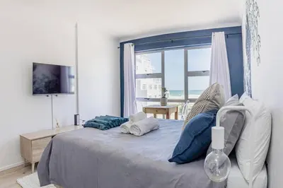 a bedroom with a large bed with a large window at Beach & Sea View Facing Apartment Japanese Styled in Cape Town
