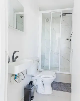 a white bathroom with a toilet and a sink at Beach & Sea View Facing Apartment Japanese Styled in Cape Town