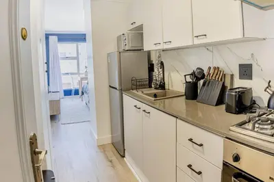 a kitchen with white cabinets and a refrigerator at Beach & Sea View Facing Apartment Japanese Styled in Cape Town