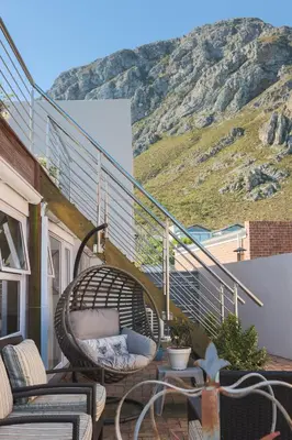 a balcony with chairs and a table and a mountain at Inn 201 in Hermanus