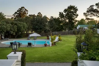 a backyard with a swimming pool and green grass at La Felicita Boutique Self Catering Villas in Somerset West