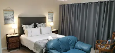 a bedroom with a bed and a blue chair at Mila's at Panorama in Panorama