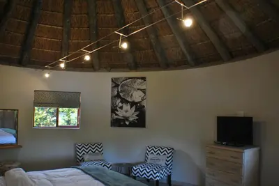 a bedroom with a bed and two chairs and a tv at Roundhouse Guesthouse in Franschhoek