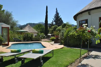 a backyard with a swimming pool and a house at Roundhouse Guesthouse in Franschhoek