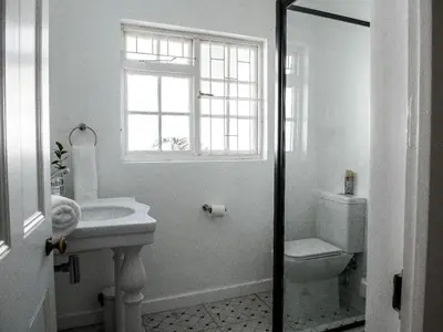 a bathroom with a sink and a toilet and a window at Petites Bulles Lodge in Stellenbosch