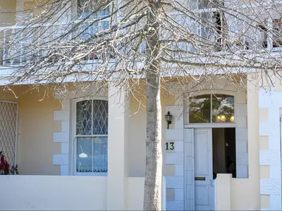 a white house with a tree in front of it at Petites Bulles Lodge in Stellenbosch