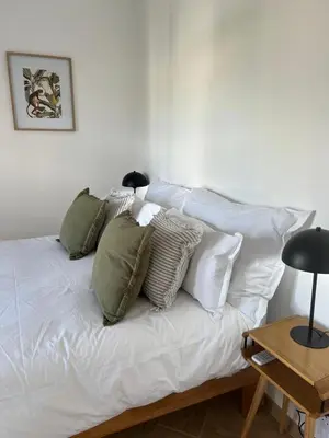 a white bed with a bunch of pillows on it at Chasselas Self Catering in Cape Town
