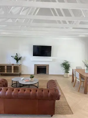a living room with a brown couch and a tv at Chasselas Self Catering in Cape Town