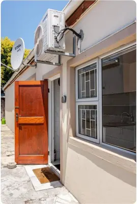 a house with a wooden door and a window at A Room with private Entrance in Cape Town