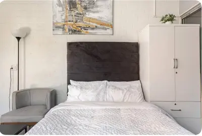 a bedroom with a bed and a chair and a painting at A Room with private Entrance in Cape Town