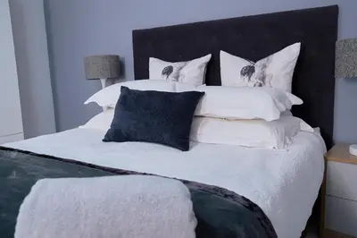 a bedroom with a large bed with white sheets and pillows at Blomtuin Sleep and go room in Cape Town