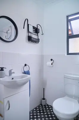 a bathroom with a white toilet and a sink at Blomtuin Sleep and go room in Cape Town