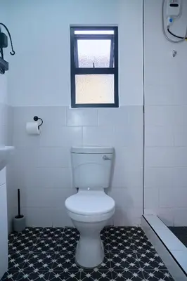 a bathroom with a white toilet and a window at Blomtuin Sleep and go room in Cape Town