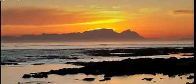 a sunset on the beach with the ocean at Piece of Paradise in Cape Town