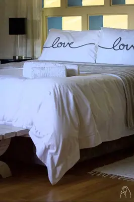 a bed with white sheets and pillows with the words love at Piece of Paradise in Cape Town
