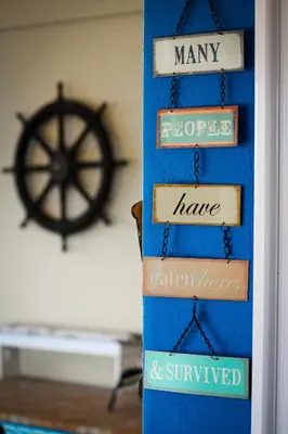 a group of signs on a blue wall with a ships wheel at Piece of Paradise in Cape Town