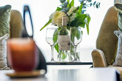 a bottle of wine and glasses on a table with flowers at 9 On The Waves in Cape Town
