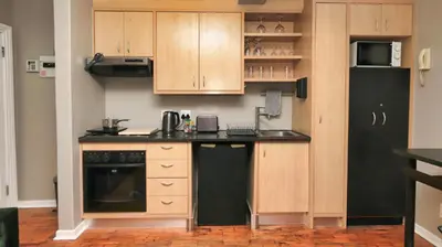 a kitchen with wooden cabinets and a black refrigerator at Royal Beauty in Paarl