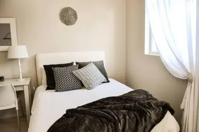 a bedroom with a white bed with pillows and a window at Olive Grove on Provident in Cape Town