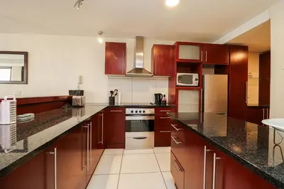 a kitchen with wooden cabinets and a stove top oven at Ocean View 304 Luxury Self Catering Apartment Strand Western Cape South Africa in Cape Town