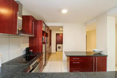 a kitchen with wooden cabinets and a black counter top at Ocean View 304 Luxury Self Catering Apartment Strand Western Cape South Africa in Cape Town