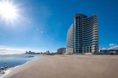a building on the beach next to the ocean at Ocean View 304 Luxury Self Catering Apartment Strand Western Cape South Africa in Cape Town