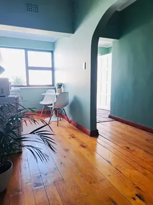 an empty room with a table and chairs on a wooden floor at Rondebosch Cottage in Cape Town