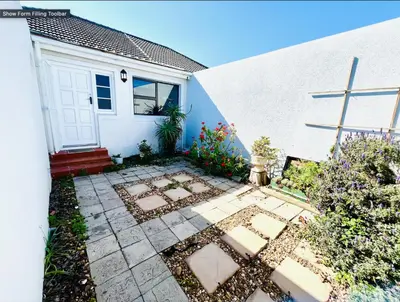 a house with a white door and a courtyard at Rondebosch Cottage in Cape Town