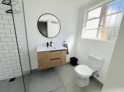 a bathroom with a toilet and a mirror at Rondebosch Cottage in Cape Town