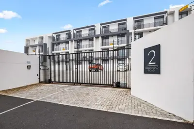 a gate to a parking lot in front of a building at Beach Break Two in Cape Town