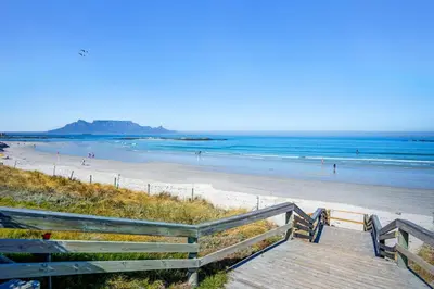 a wooden staircase leading to a beach with people at Beach Break Two in Cape Town